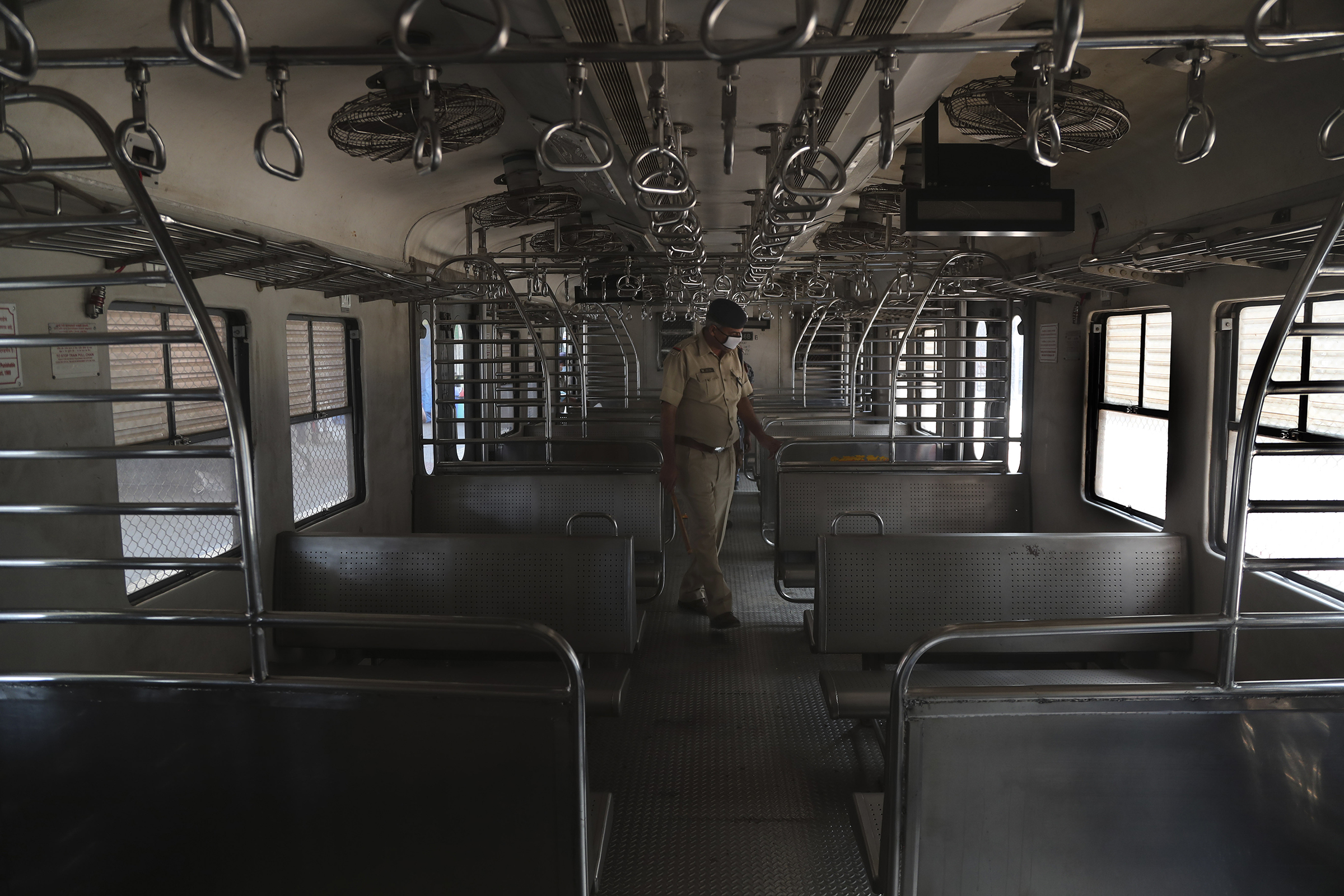 An Indian police officer wearing a mask checks a suburban train before they are locked down in Mumbai, India, on March 23, 2020.