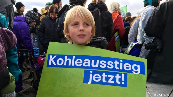 In a massive protest against coal in western Germany, a nine-year-old boy holds a banner that reads coal exit now! 