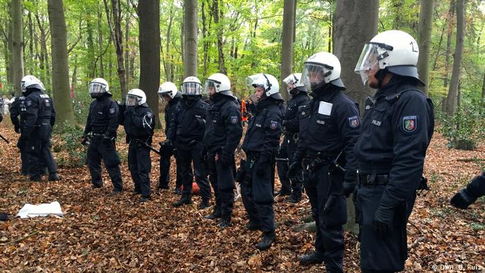 Police officers make a barrier inside the forest during a massive anti-coal protest in western Germany. They prevent protesters from going in that direction