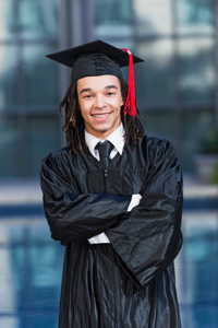 Boy of secondary school age wearing graduation gown